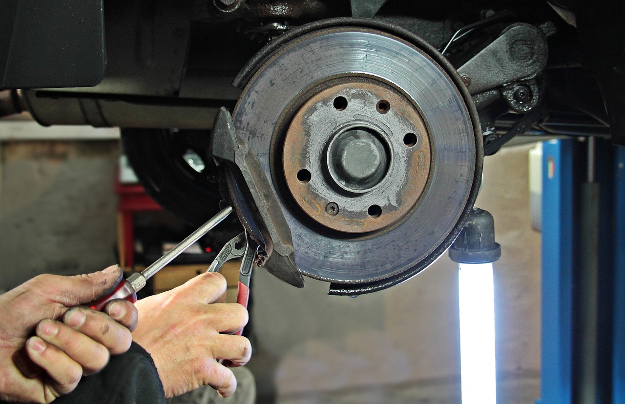 A mechanic's hands servicing a car's front brake disc